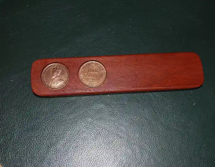 A flat wooden two-up kip with two 1915 Australian pennies resting on it